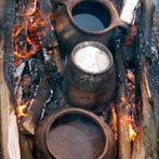 Koken in potten, met aan beide zijden vuur. (klik voor een uitvergroting)